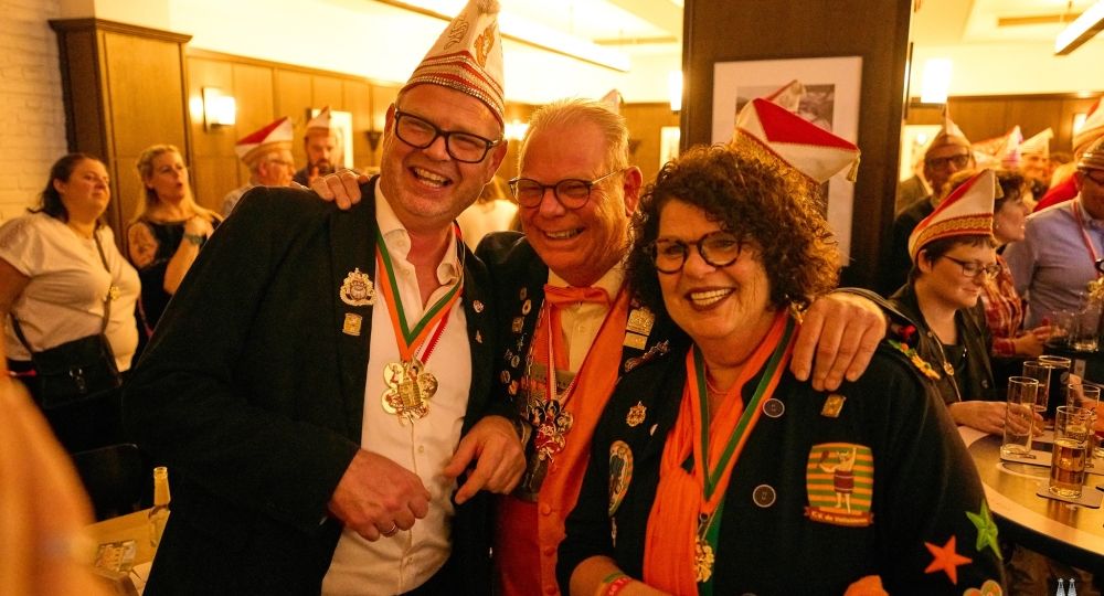 Drei fröhliche Jecken feiern gemeinsam – die Stimmung ist herzlich und ausgelassen.