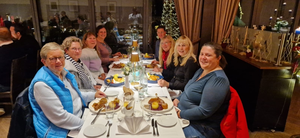 Eine fröhliche Runde genießt ein gemeinsames festliches Abendessen in weihnachtlich geschmücktem Ambiente – gute Stimmung und gemütliches Beisammensein.