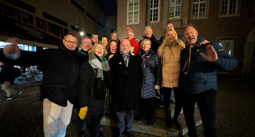 Eine fröhliche Gruppe posiert lachend im Freien bei Nacht – warme Kleidung, gute Stimmung und ausgelassene Atmosphäre prägen das gemeinsame Erlebnis.